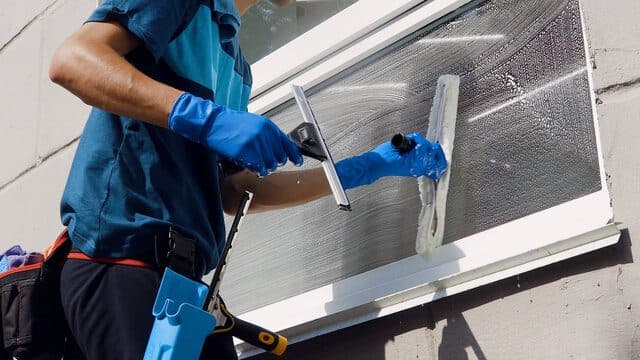 Window cleaner scrubbing exterior glass with professional tools